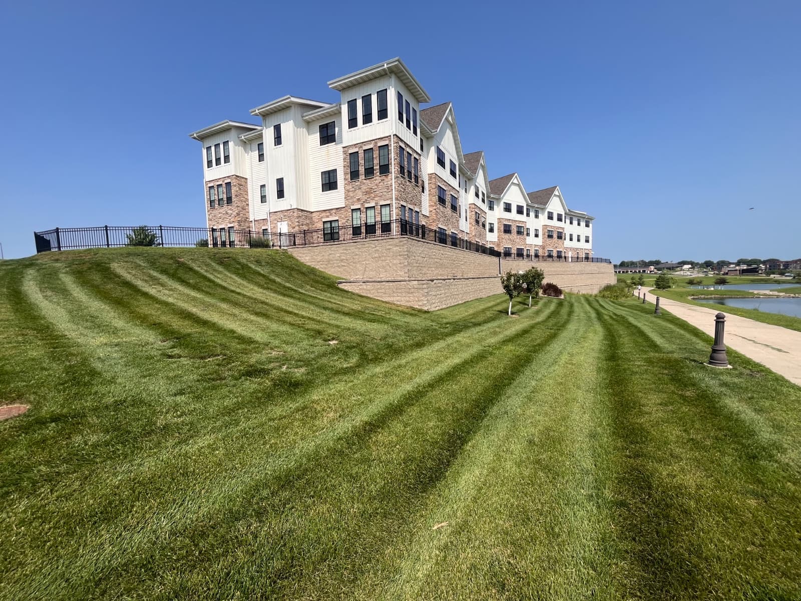 Striped green lawn beside a building and paved paths